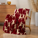 Couverture douce et chaleureuse avec motif abstrait de silhouettes humaines en blanc sur fond rouge, créant un visuel moderne et élégant dans la pièce.