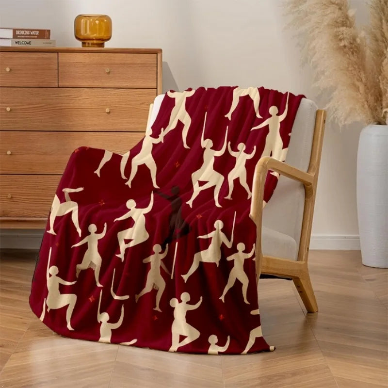 Couverture douce et chaleureuse avec motif abstrait de silhouettes humaines en blanc sur fond rouge, créant un visuel moderne et élégant dans la pièce.