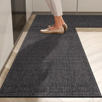 Un tapis d'entrée gris texturé avec des pieds chaussés de ballerines beiges posés dessus.