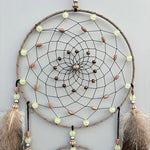 Un magnifique capteur de rêves en cercles concentriques avec des perles et des plumes créant une œuvre d'art ethnique.
