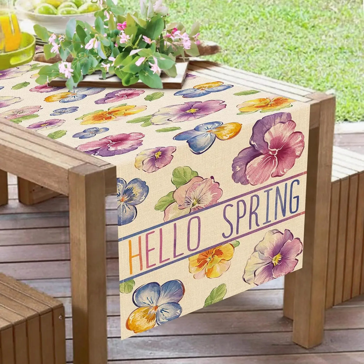 Table de jardin en bois décorée de fleurs colorées de printemps avec un message "Bonjour le printemps".