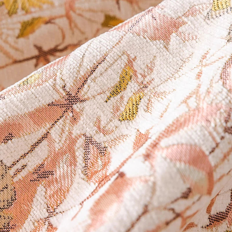 L'image montre un gros plan sur un tissu délicat et décoré de motifs floraux et de couleurs douces allant du blanc au rose et au jaune.