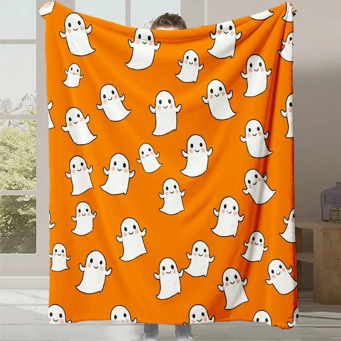 Couverture orange ornée de motifs de fantômes blancs souriants, créant une ambiance festive et ludique parfaite pour une soirée d'Halloween.