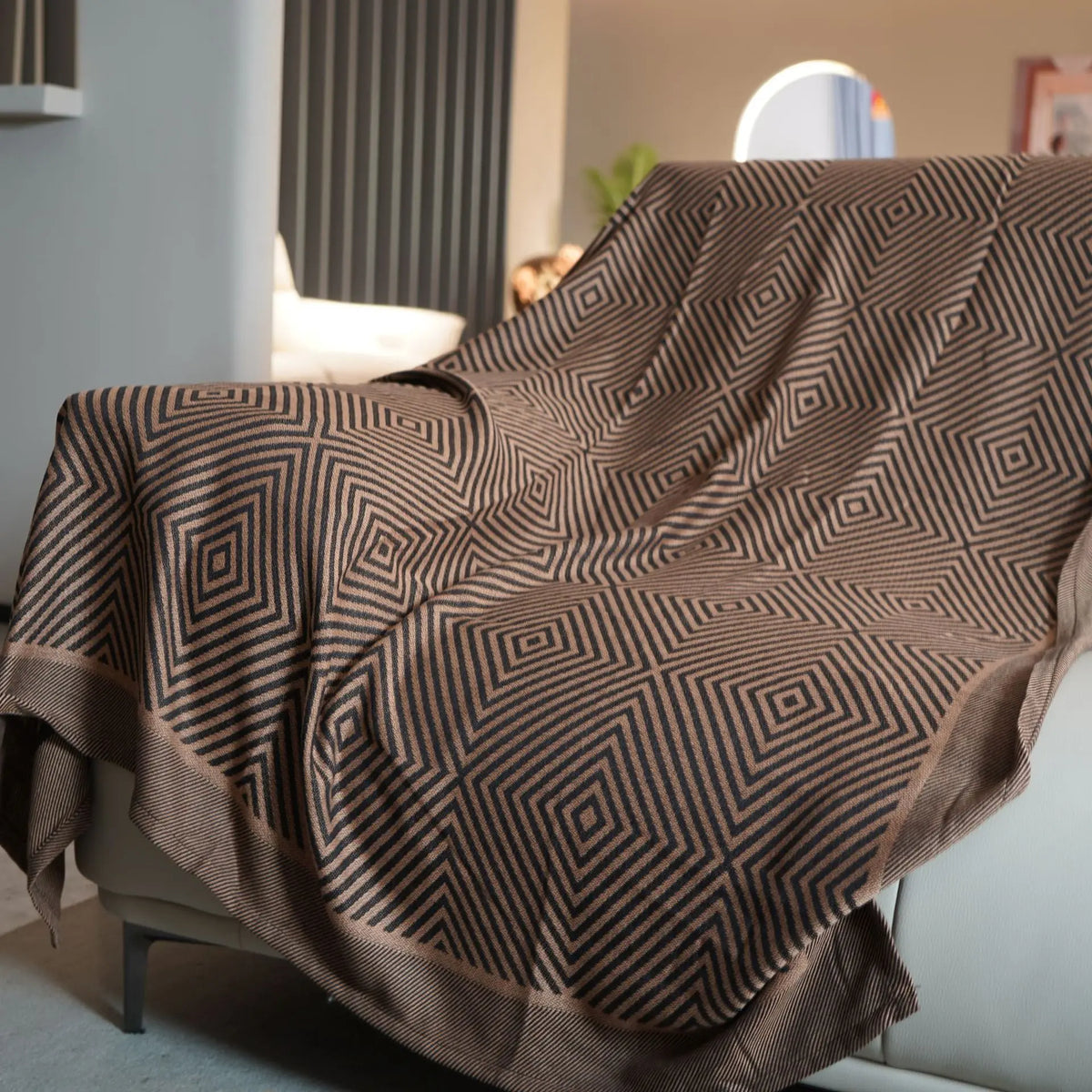 Une couverture ou un plaid avec un motif géométrique complexe en noir et blanc, évoquant une atmosphère moderne et élégante dans l'espace intérieur.