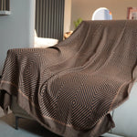 Une couverture ou un plaid avec un motif géométrique complexe en noir et blanc, évoquant une atmosphère moderne et élégante dans l'espace intérieur.