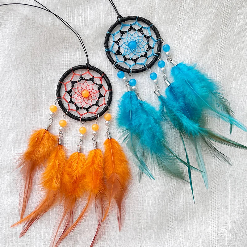 Deux attrapeurs de rêves colorés et artistiques avec des perles et des plumes bleues et orange, suspendus à un mur blanc.