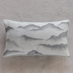 Coussin décoratif avec un motif de montagnes et de paysage brumeux, dans des tons de gris neutres, créant une ambiance apaisante et sereine.