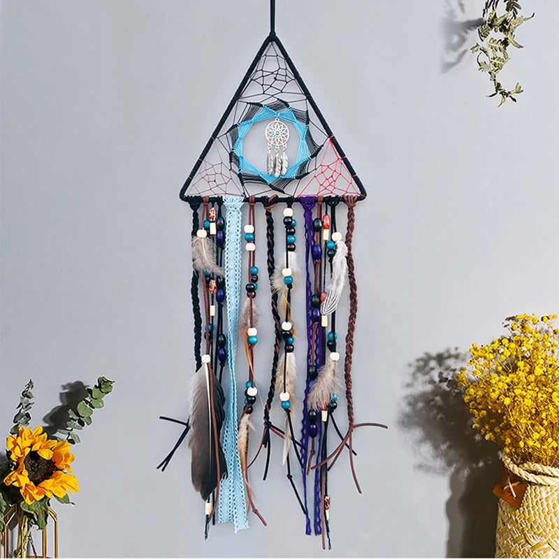 Cette image présente un magnifique attrape-rêves triangulaire décoré de plumes, de perles et d'un motif de dreamcatcher au centre.