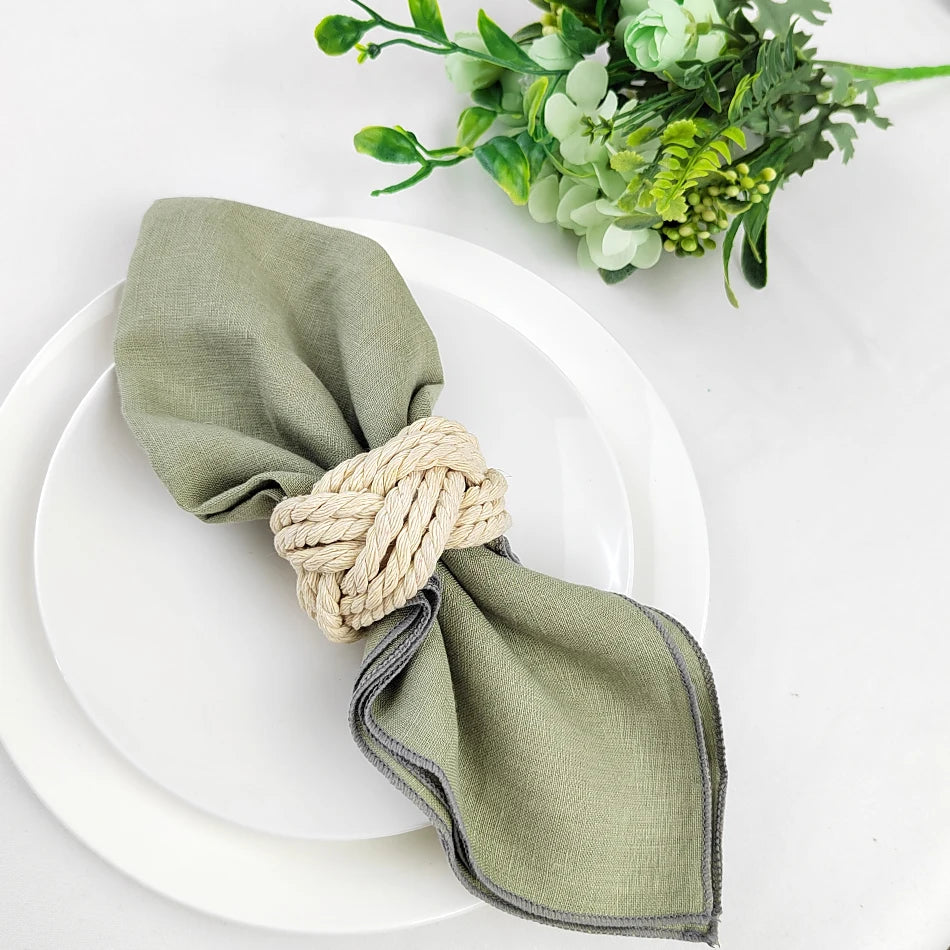 Un arrangement élégant de serviette de table verte et de cordes de jute, accompagné d'un bouquet floral verdoyant, crée une ambiance naturelle et raffinée pour la table.