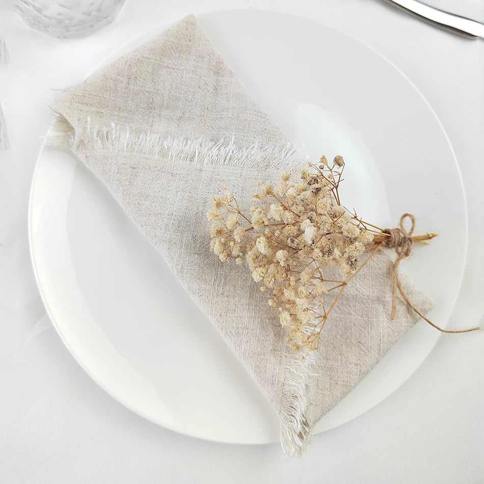Une délicate couronne de fleurs séchées sur une serviette de lin grise décore élégamment la table.