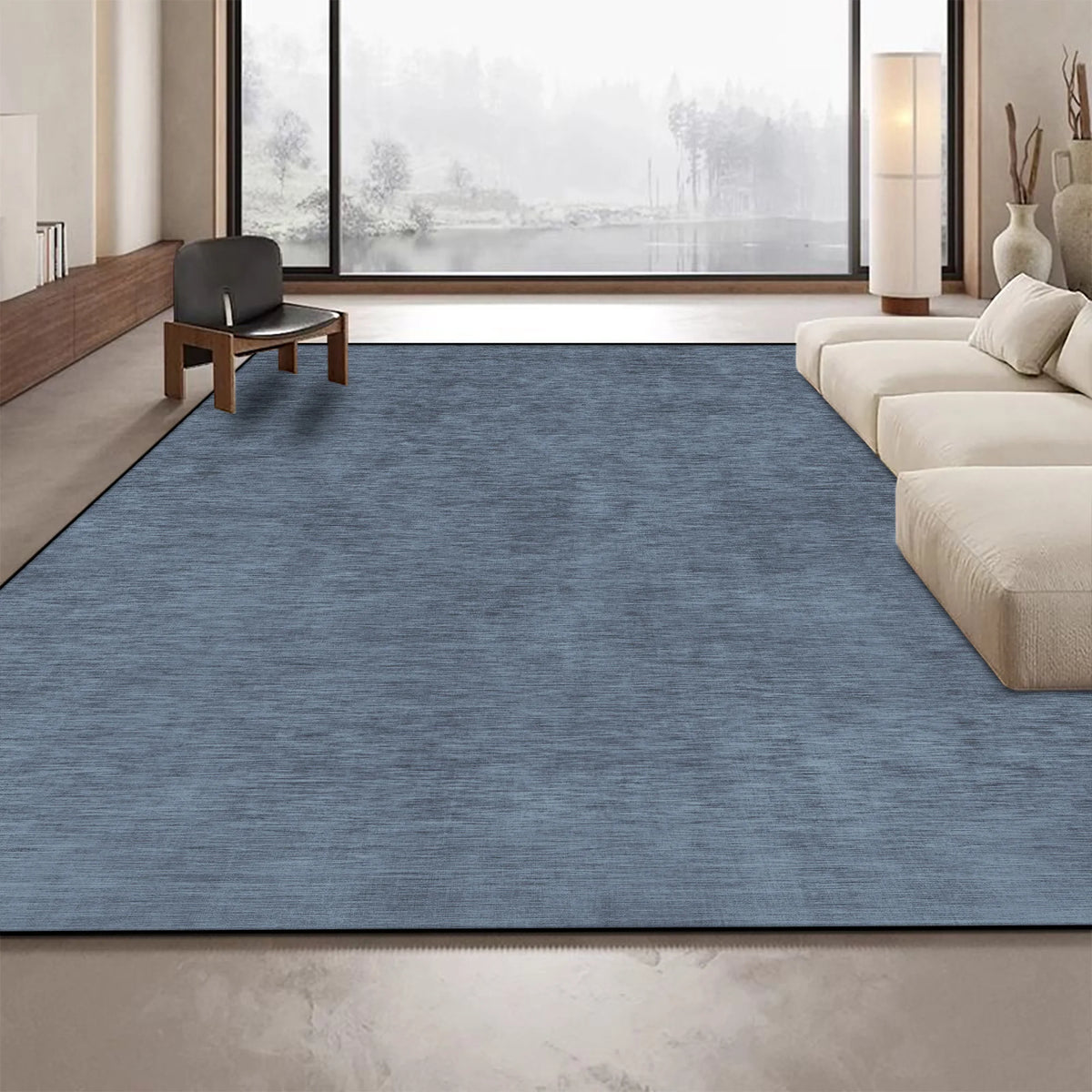 Ce tapis en bleu foncé ajoute une touche de sophistication et de chaleur à cet espace de vie moderne et épuré, offrant un contraste harmonieux avec les tons neutres et les grandes fenêtres.