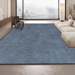 Ce tapis en bleu foncé ajoute une touche de sophistication et de chaleur à cet espace de vie moderne et épuré, offrant un contraste harmonieux avec les tons neutres et les grandes fenêtres.
