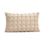 Un coussin décoratif beige crème avec des motifs géométriques en relief, créant une texture intéressante.