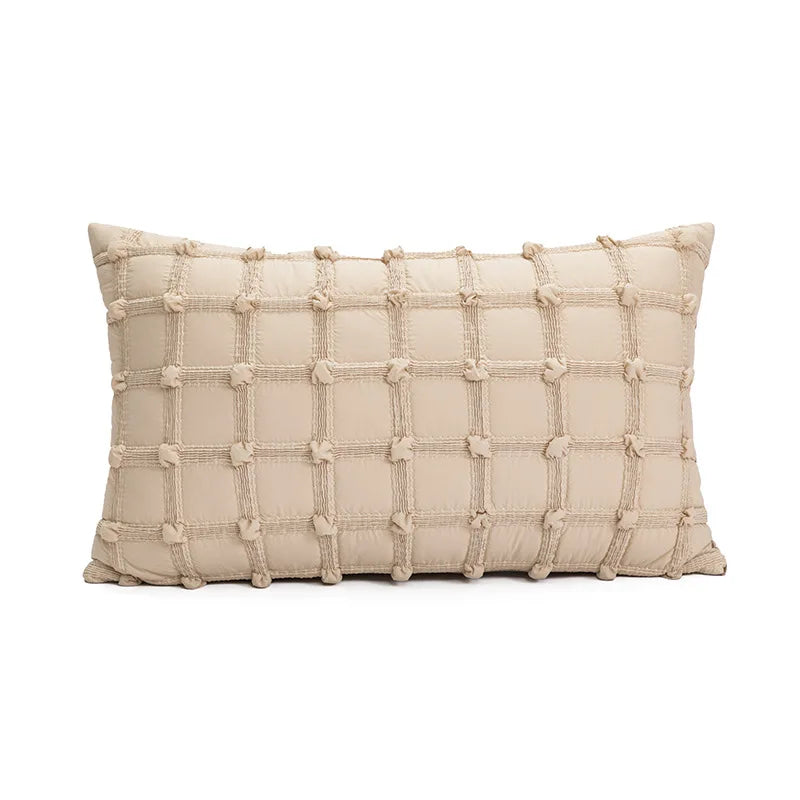 Un coussin décoratif beige crème avec des motifs géométriques en relief, créant une texture intéressante.