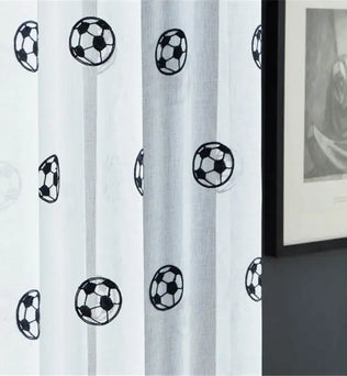 Zoom sur le tissu du rideau montrant des motifs de ballons de football avec effet de transparence.