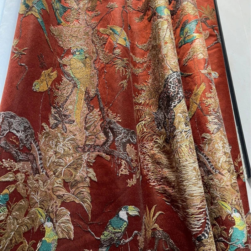 Zoom sur le tissu du rideau tropical, présentant des toucans, jaguars et feuillages brodés sur un fond rouille intense.