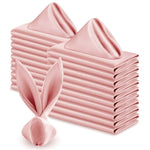 Ensemble de serviettes de table pliées en forme de triangles roses, disposées avec soin les unes sur les autres, créant une image élégante et harmonieuse.