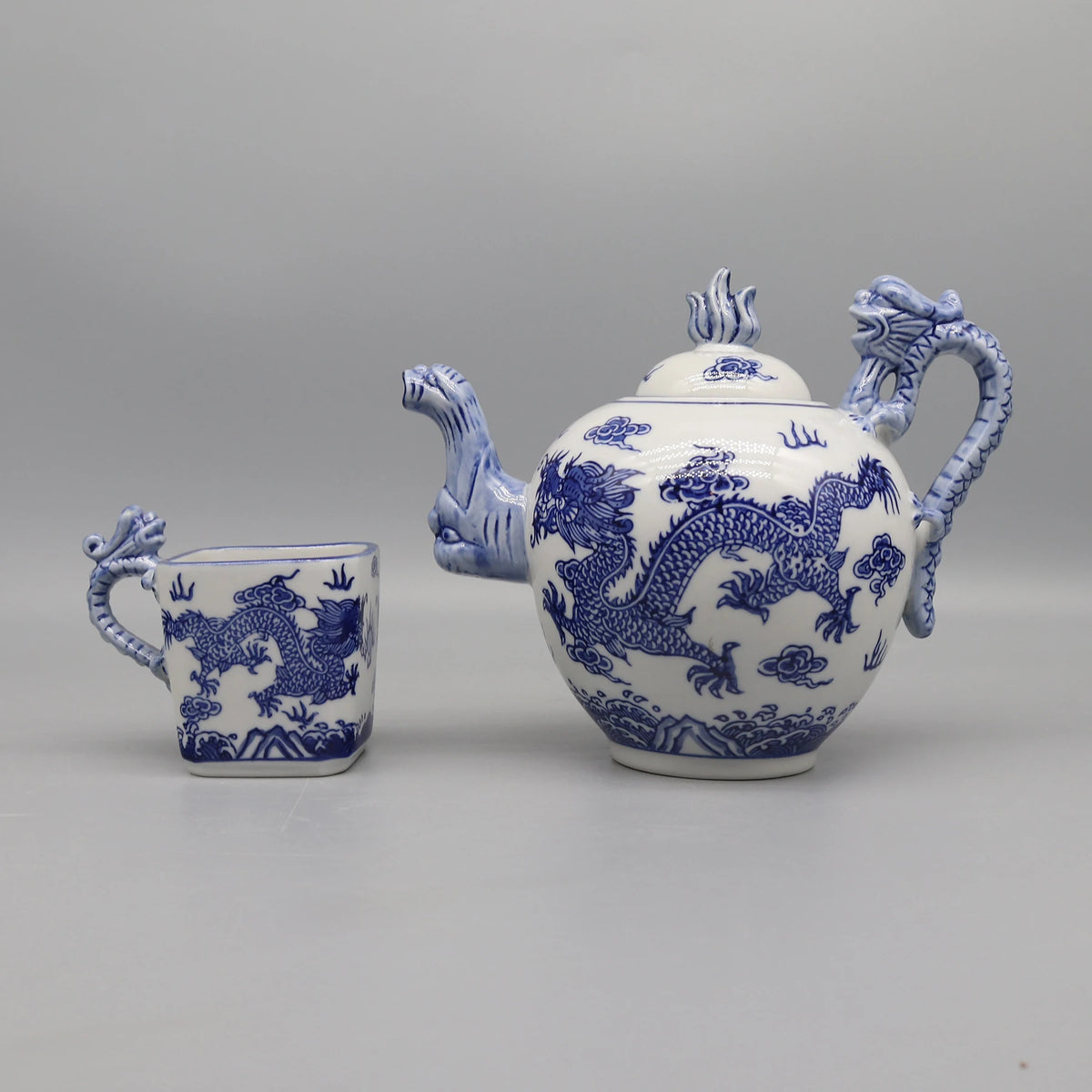 Un service à thé décoratif avec des motifs de dragons bleus et blancs, composé d'une théière et d'une tasse caractéristiques de l'artisanat traditionnel chinois.