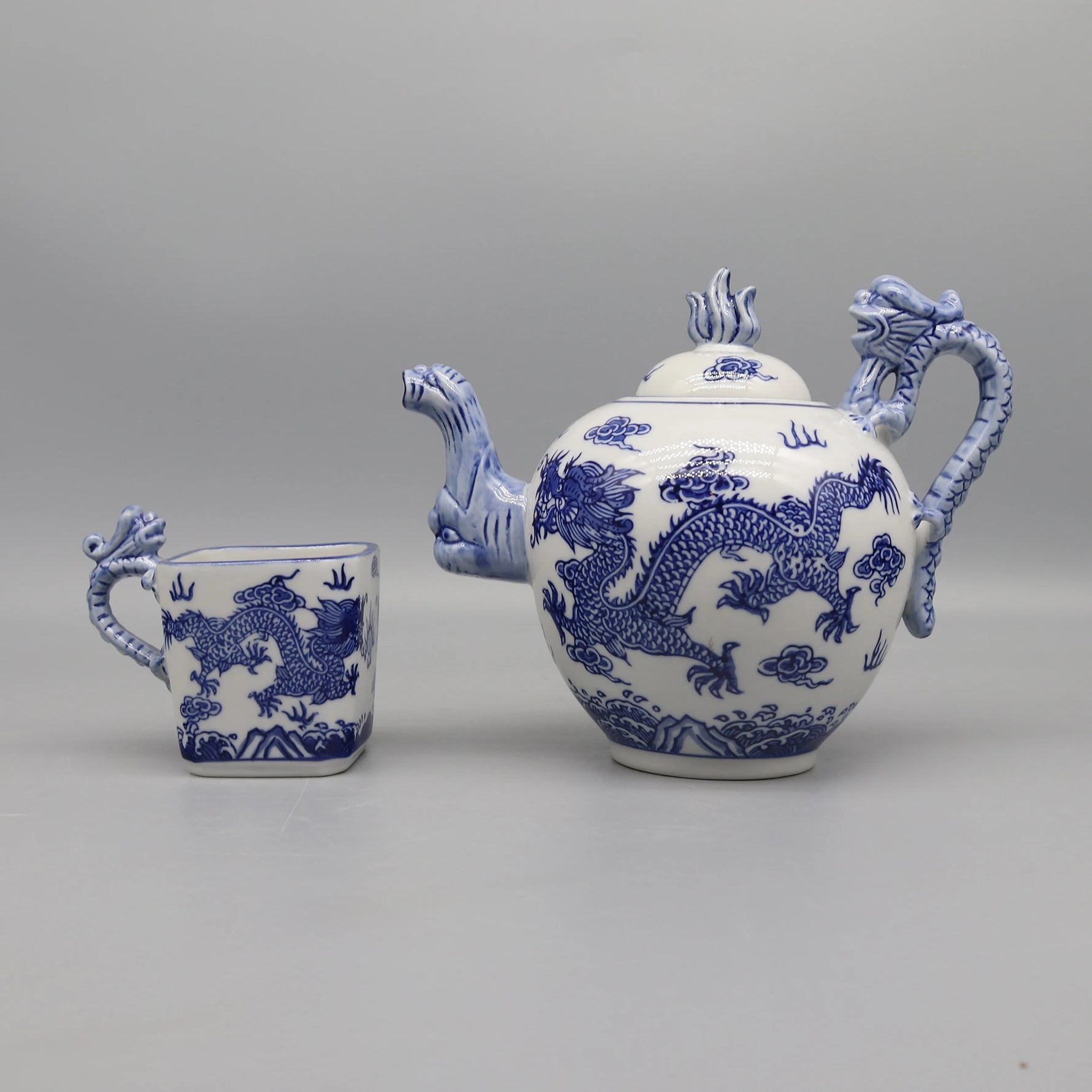 Un service à thé décoratif avec des motifs de dragons bleus et blancs, composé d'une théière et d'une tasse caractéristiques de l'artisanat traditionnel chinois.