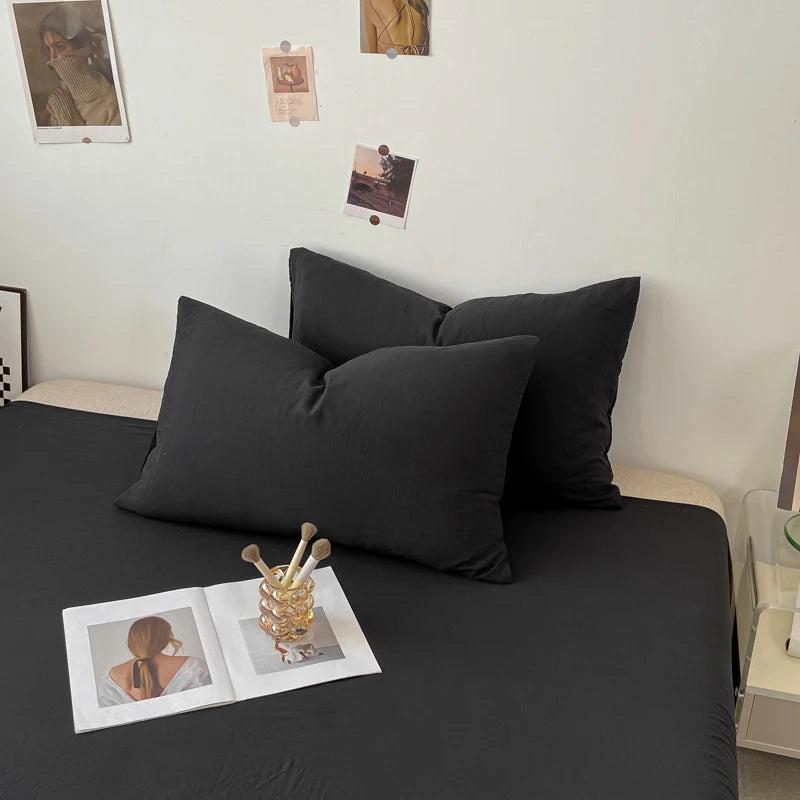 La chambre moderne présente un canapé noir matelassé avec des coussins assortis, des photos encadrées sur le mur et des accessoires décoratifs sur la table basse, créant une ambiance épurée et élégante.