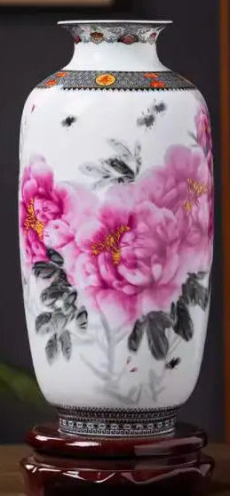 Un magnifique vase en porcelaine blanche orné de fleurs de pivoines roses épanouies, sur un socle en bois sombre.