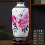 Un magnifique vase en porcelaine blanche orné de fleurs de pivoines roses épanouies, sur un socle en bois sombre.