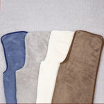 Une variété de tapis de bain aux couleurs neutres et relaxantes, offrant un confort douillet et un style élégant dans la salle de bain.