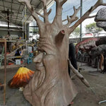 sculpture arbre anthropomorphique feuilles colorées marron vert orange texture bois yeux jaunes sourire