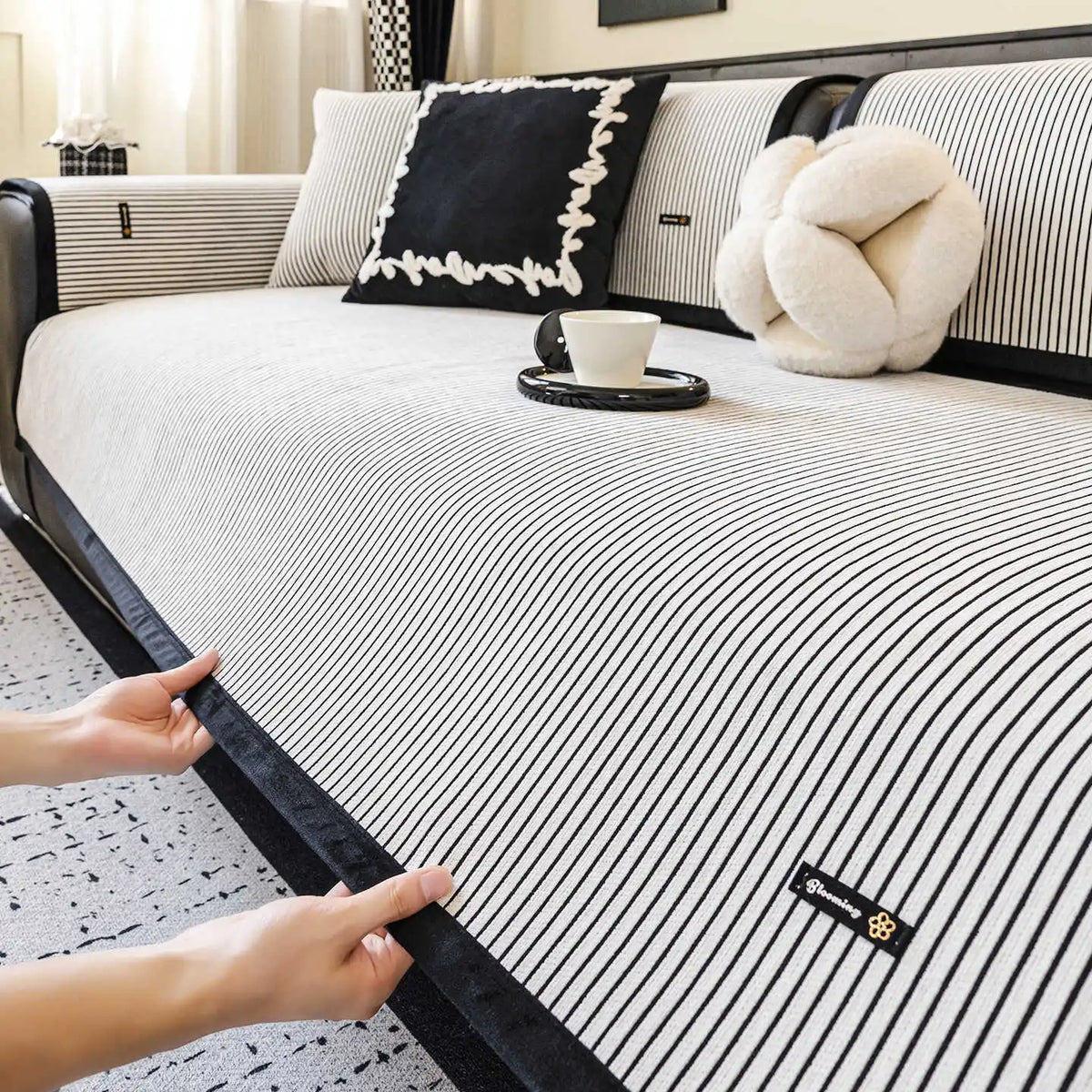 Une chambre lumineuse et épurée avec un lit aux draps rayés, des coussins noirs et blancs ainsi qu'un doux ours en peluche, le tout sur un tapis à motifs.