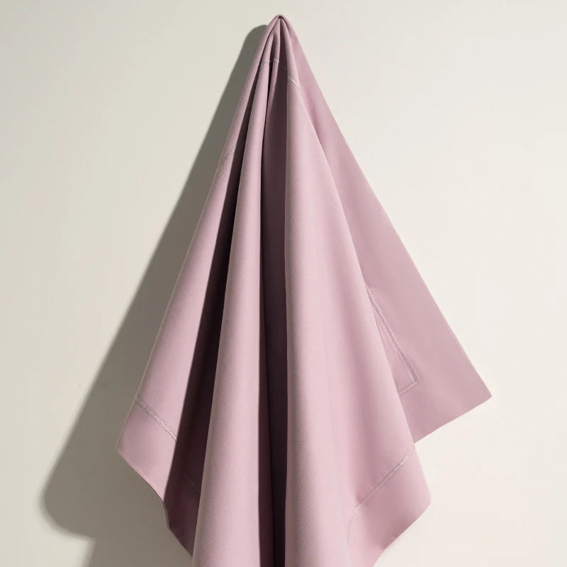 Une serviette en coton rose pâle pliée avec style et élégance, prête à être utilisée pour un moment de détente ou de fraîcheur.