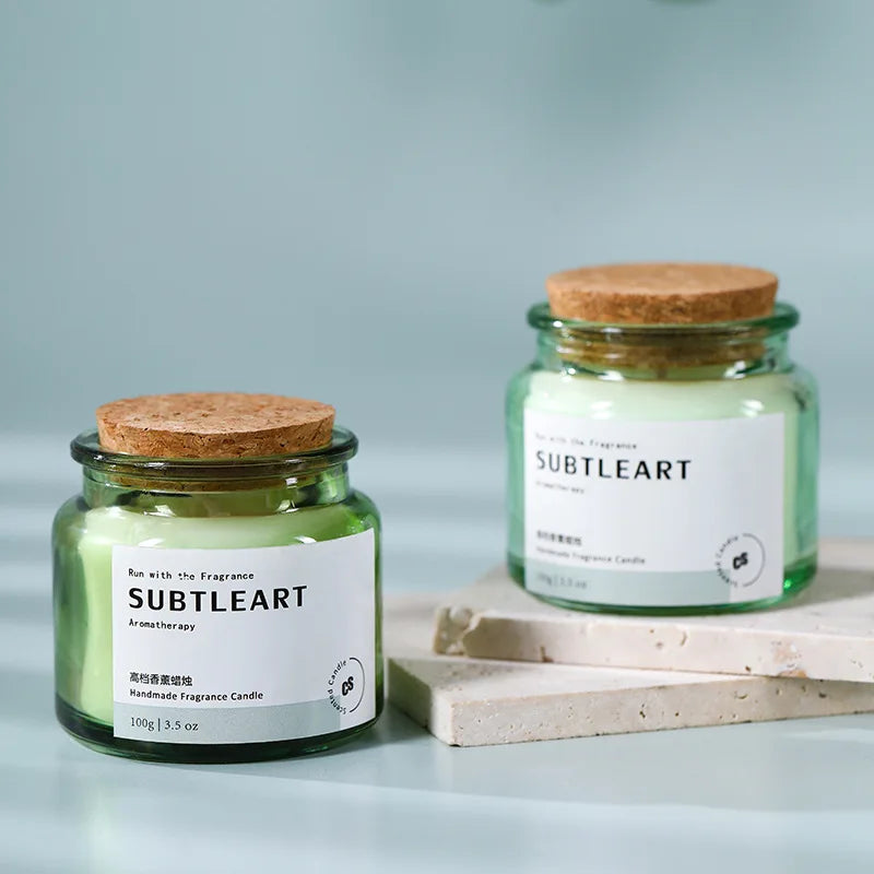 Deux bocaux en verre de bougies parfumées artisanales Subtleart sur une surface en marbre clair.