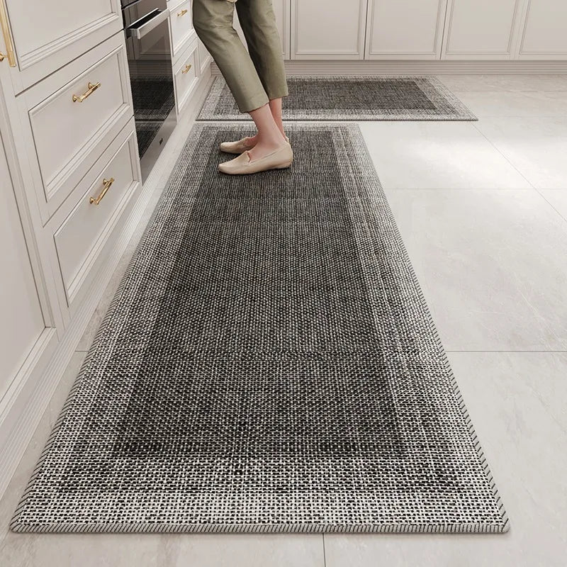 Tapis de couloir gris texturé s'étendant sur le sol d'une cuisine, avec des pieds chaussés de mocassins traversant la scène.