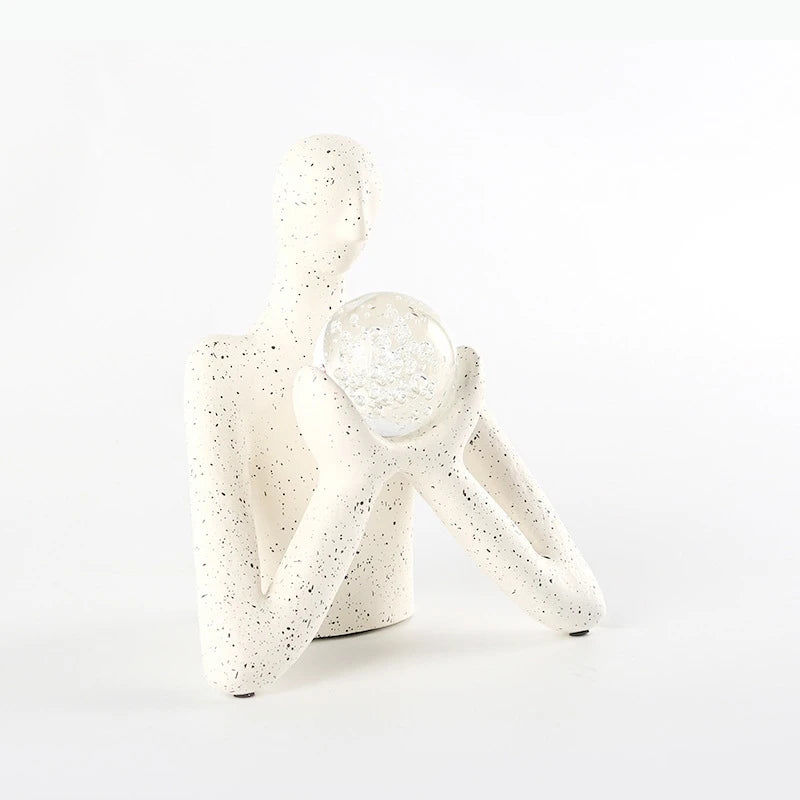statue décorative personnage humain sphère transparente motifs internes neige cristaux blanc taches noires.texture granuleuse