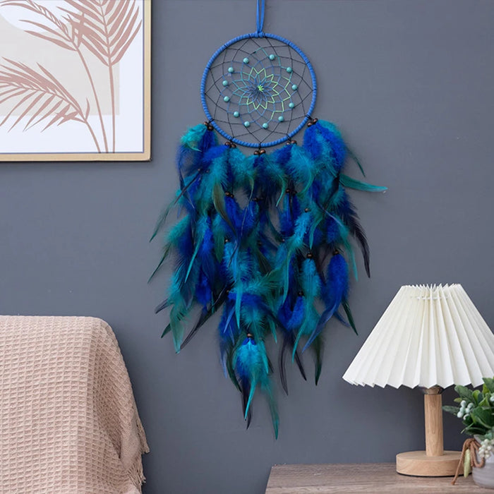 Capteur de rêves bleu et vert décoré de plumes dans un cadre intérieur aux murs gris.