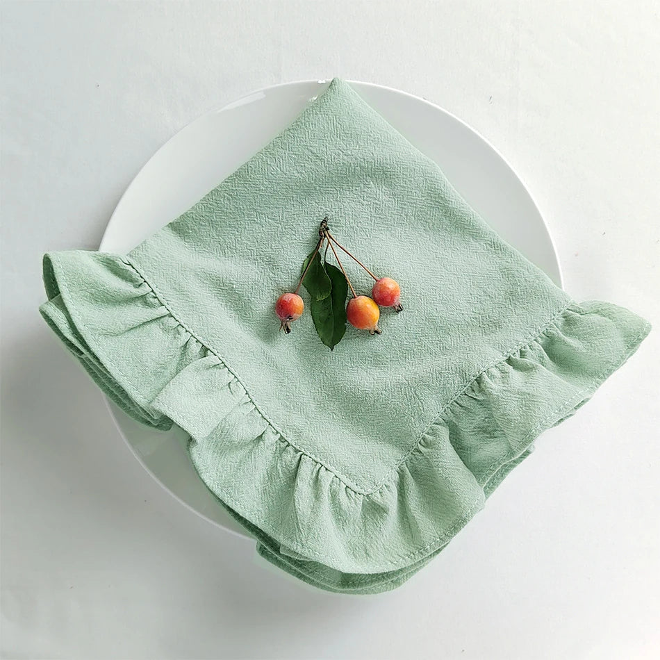 Magnifique serviette de table vert menthe ornée de quelques baies rouges et feuilles vertes, créant une belle présentation élégante.
