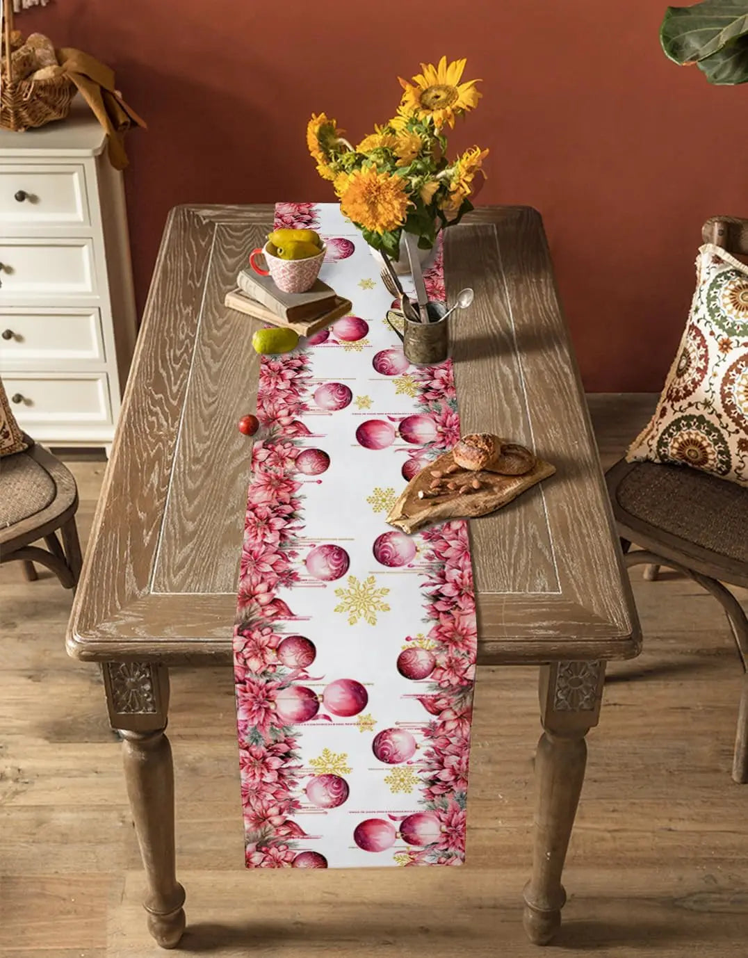 Cette table de salle à manger rustique est ornée d'un chemin de table coloré avec des motifs de fleurs et de fruits, complété par un vase de fleurs jaunes et des accessoires décoratifs.