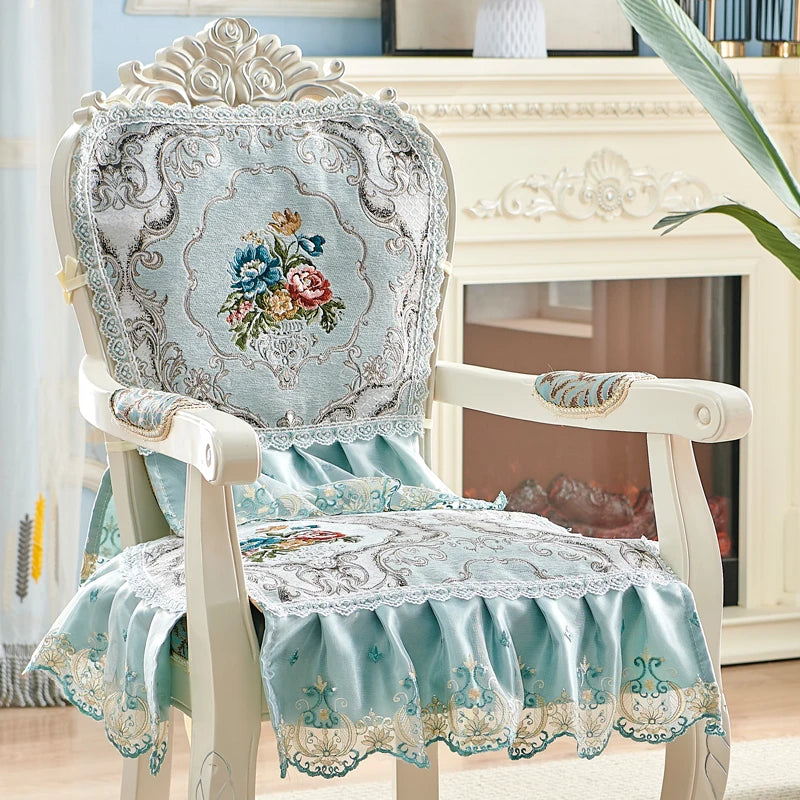 Élégant fauteuil vintage tapissé de motifs floraux en ton bleu pastel, orné de dentelle et de détails ouvragés, dans un décor intérieur lumineux.