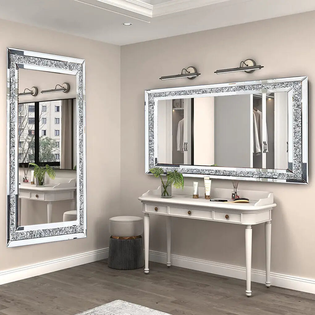Élégante salle de bain avec un miroir orné de détails scintillants, un meuble blanc avec des tiroirs, des appliques murales et des plantes vertes qui créent une atmosphère chaleureuse et raffinée.