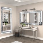 Élégante salle de bain avec un miroir orné de détails scintillants, un meuble blanc avec des tiroirs, des appliques murales et des plantes vertes qui créent une atmosphère chaleureuse et raffinée.