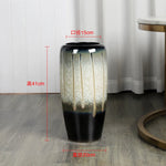 Un vase en céramique orné de motifs gris et noirs, mesurant 41 cm de hauteur et 15 cm de diamètre.