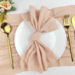 Une table de dîner élégante avec une assiette blanche, des couverts dorés et une serviette rose nouée de manière décorative.