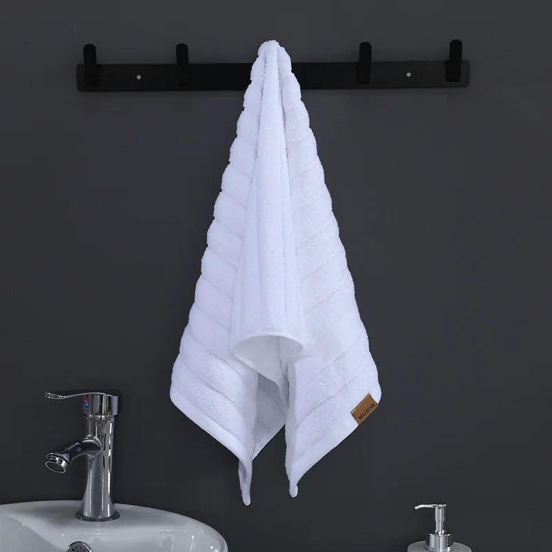 Une serviette blanche suspendue à un porte-serviettes noir, installé à côté d'un évier en métal moderne.