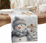 Une table de Noël élégante avec une décoration hivernale et un bonhomme de neige souriant tenant une pancarte "Joyeux Noël".