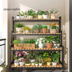 Étagère à plantes en métal et bois couleur vert sur un balcon ensoleillé