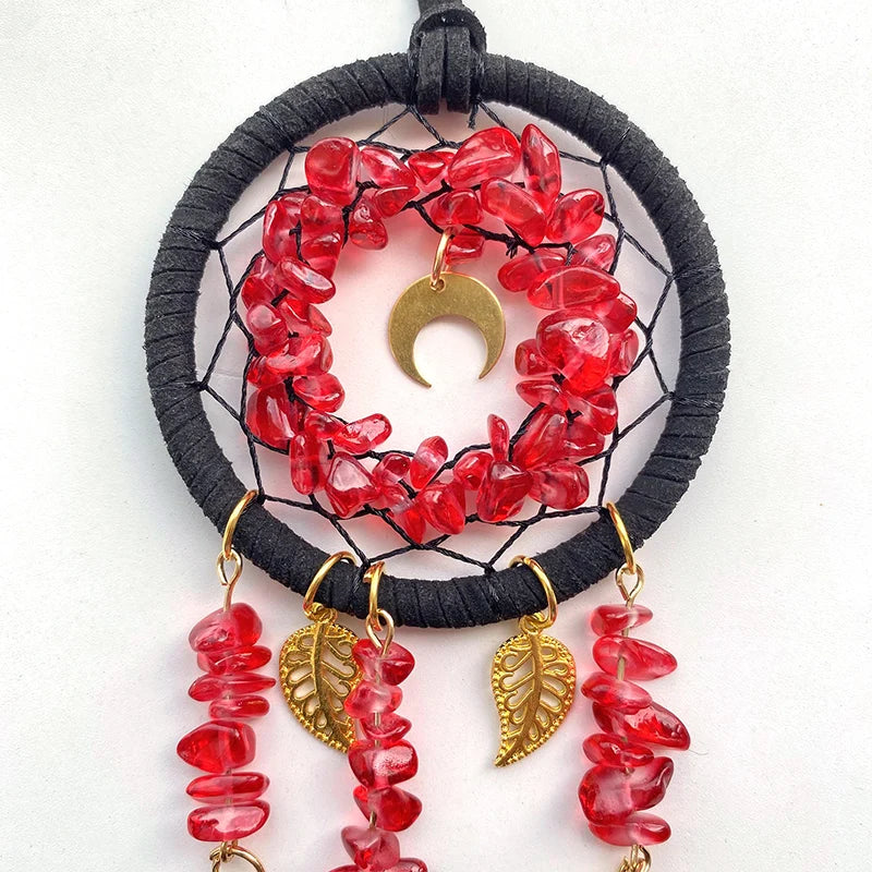 Attrape-rêves décoratif en forme de lune avec des pierres rouges et des pendentifs en feuille d'or.
