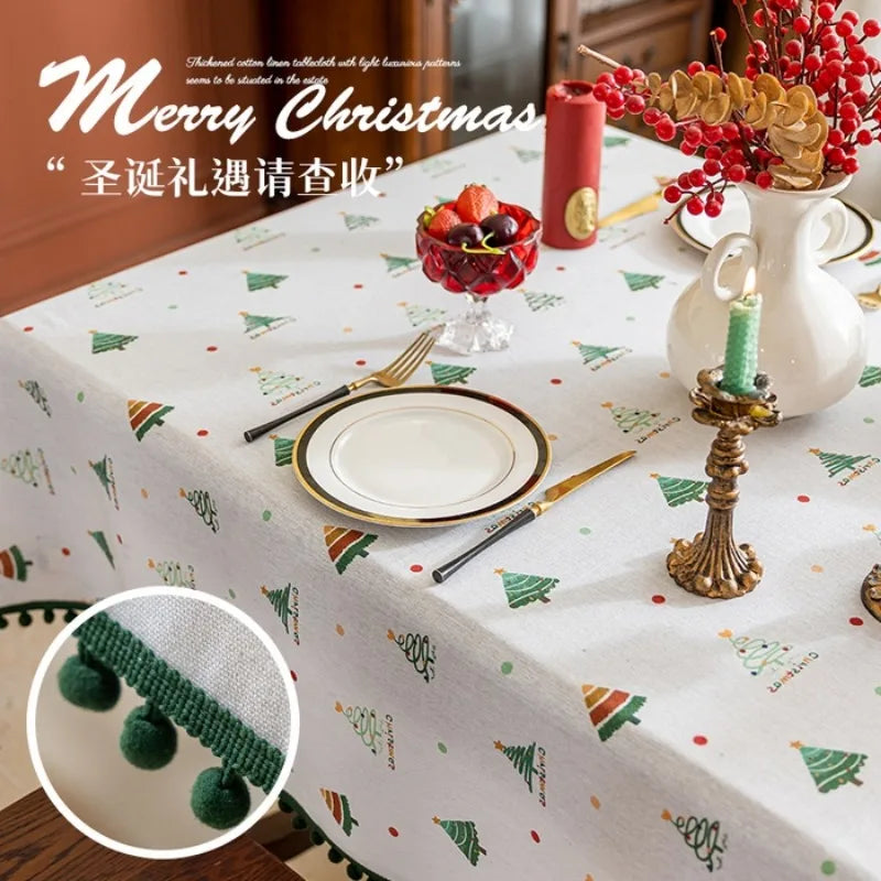 Une table de fête de Noël décorée de motifs de sapins et de baies rouges, avec des couverts dorés et un bougeoir sur la nappe.