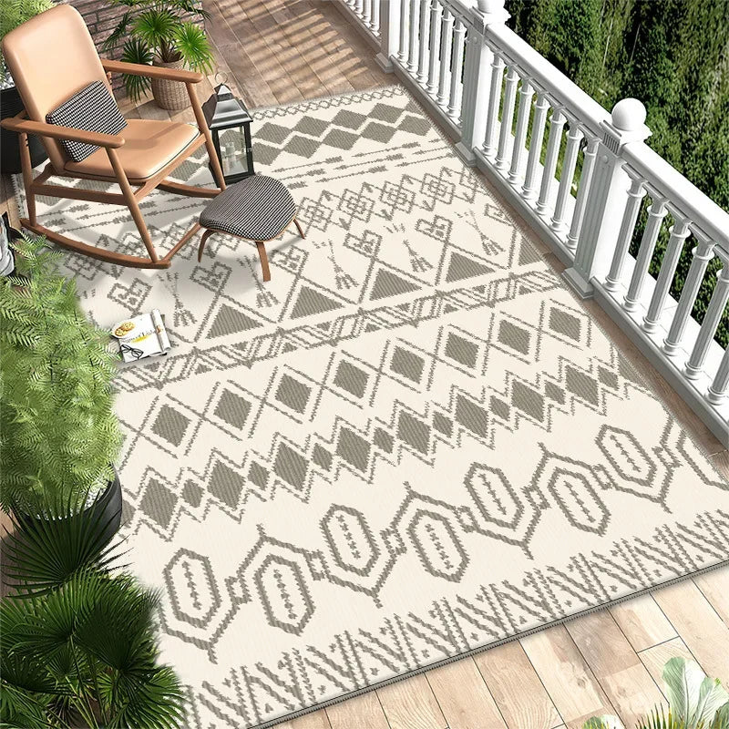 Tapis géométrique beige et gris sur un parquet en bois entouré de plantes tropicales sur un porche apaisant.