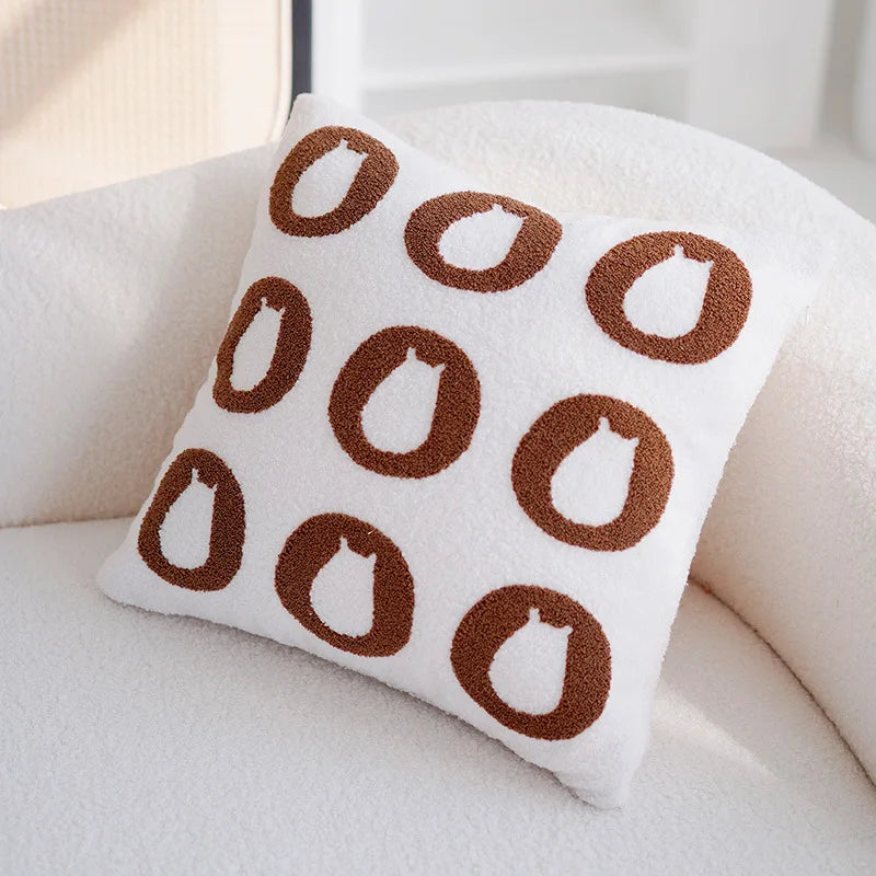 Un oreiller blanc avec des imprimés circulaires marron, offrant un aspect moderne et géométrique.