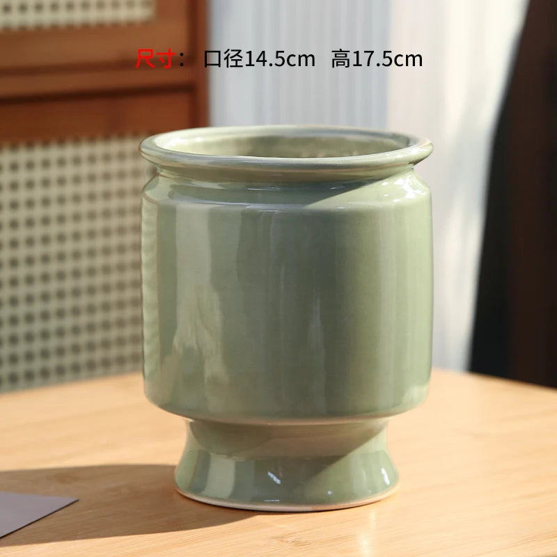 Vase en céramique vert pâle avec des dimensions de 14,5 cm de diamètre et 17,5 cm de hauteur, conçu pour être un accessoire décoratif élégant dans un intérieur.