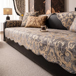 Le canapé est recouvert d'un motif floral et ondulé de teintes brunes et dorées, créant une atmosphère chaleureuse et élégante dans la pièce.